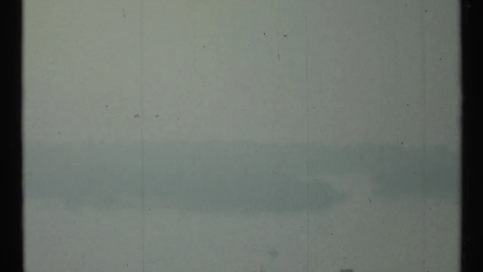 Muted 1967 Toronto harbor frame with fog across open water and faint waterfront forms near the horizon.