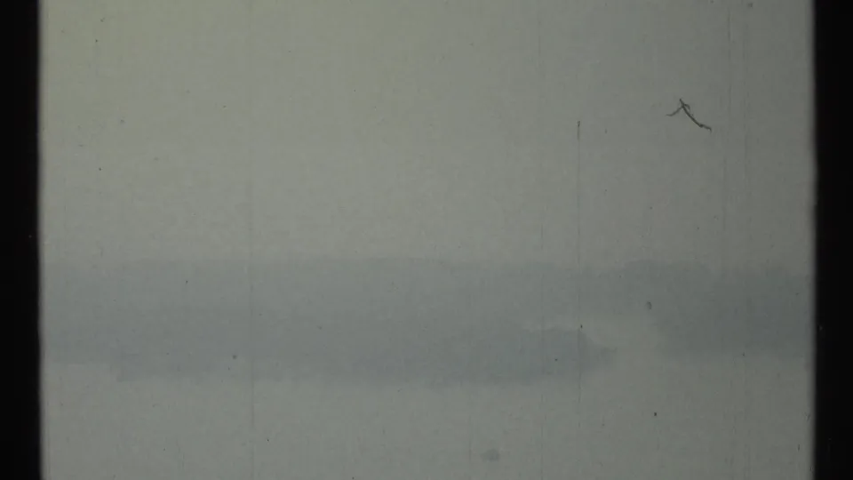 Final 8mm frame of the Toronto harbor view, with mist obscuring shoreline detail and no visible people.