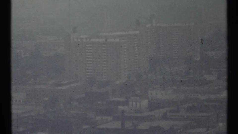 1967 Toronto skyline view with high-rise buildings partly obscured by fog and soft 8mm grain.