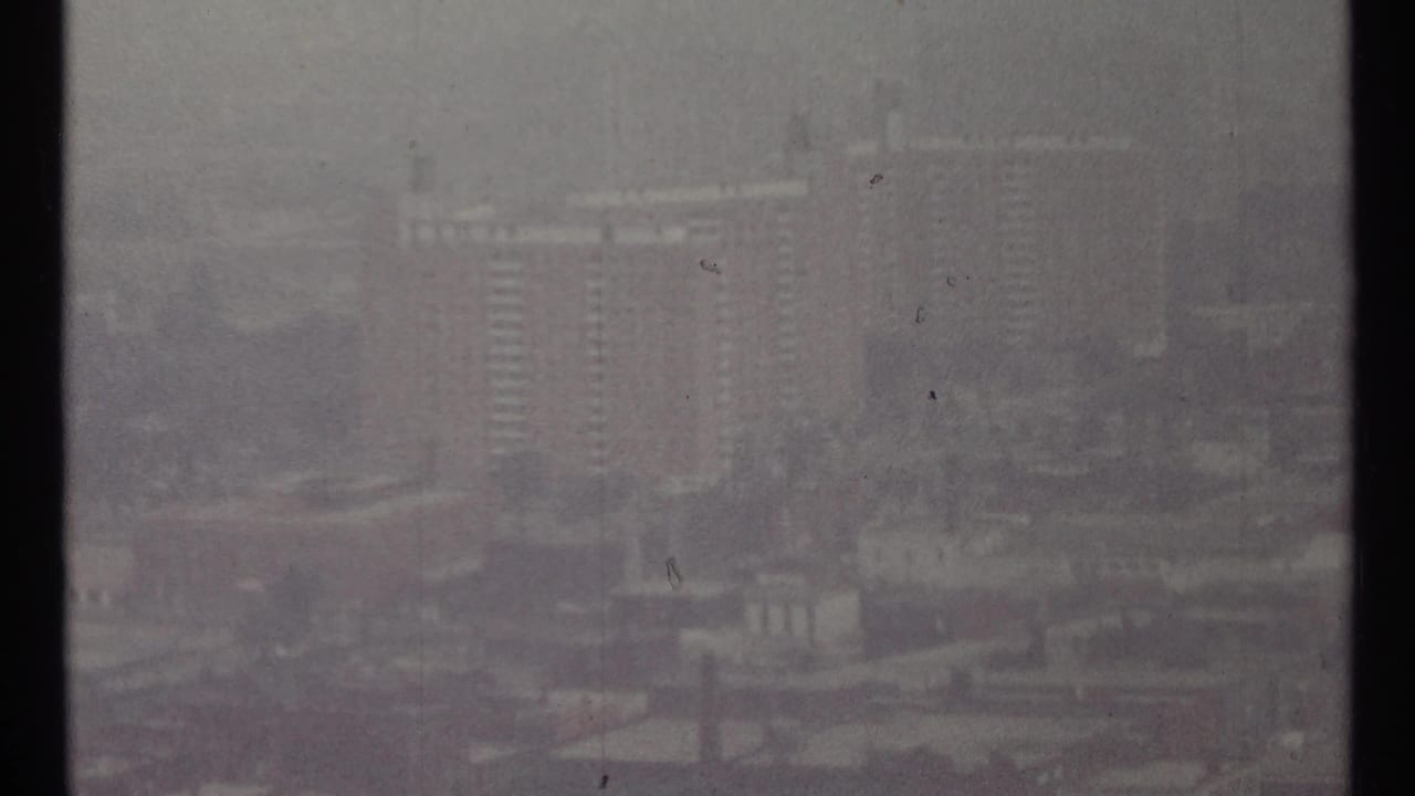 Foggy city skyline with tall buildings and muted urban forms.