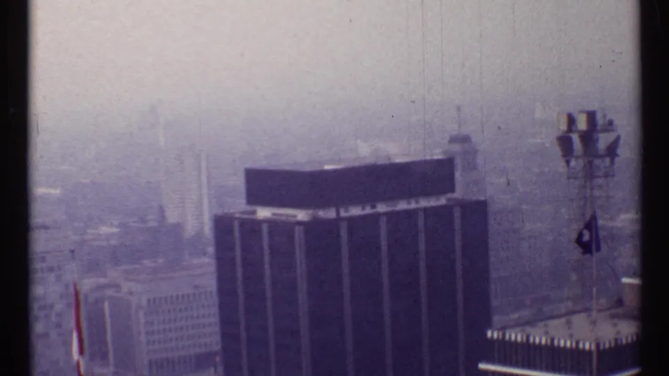 1967 Toronto skyline from an elevated vantage, with rooftop chimneys and high-rises fading into haze.