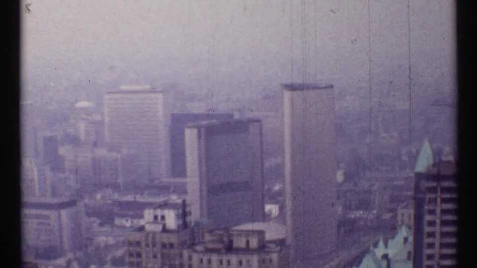 1967 Toronto 8mm frame looking over multiple downtown high-rises and rooftops in thick haze.