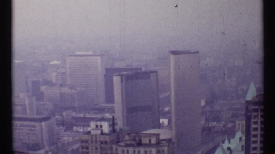 1967 Toronto skyline in hazy light, with mid-century high-rises and soft purple 8mm film color.