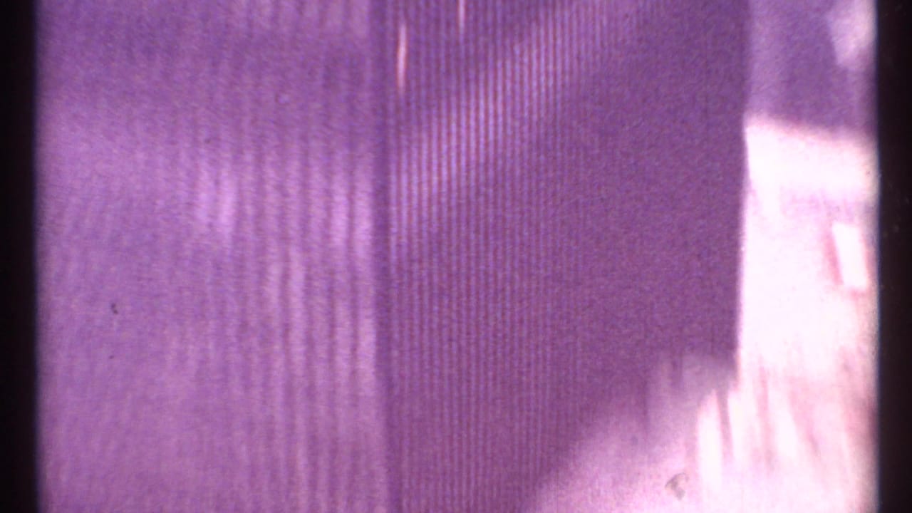 Abstract close view of film grain, vertical lines, and a bright blurred strip.