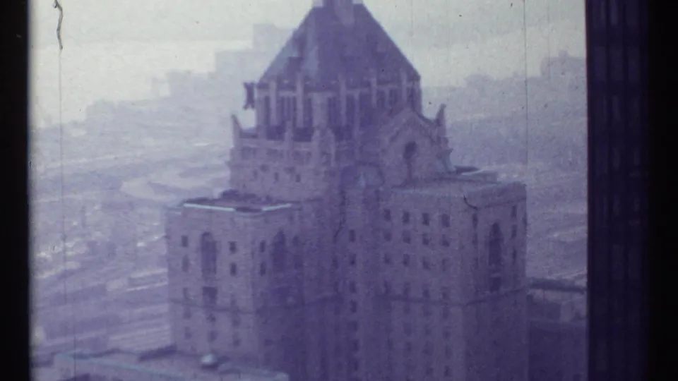 1967 Toronto view of an ornate historic-looking tower rising through haze, with streets and darker buildings in the background.