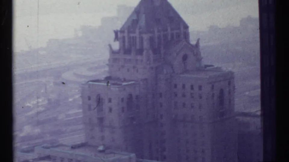 1967 Toronto 8mm frame showing a large Gothic-style building near a broad rail yard under overcast light.