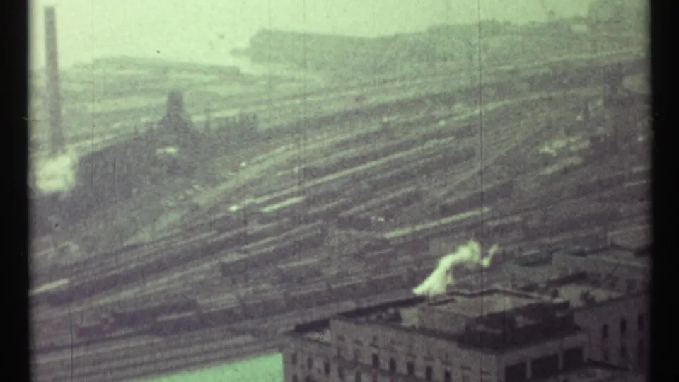 1967 Toronto view across an industrial rail yard with freight cars, low roofs, and white smoke from a tall stack.
