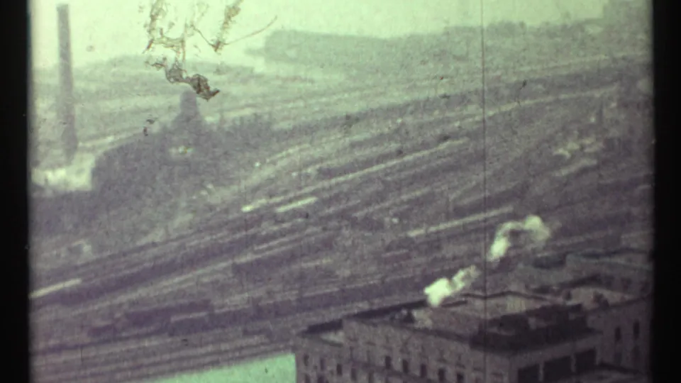 Final 1967 Toronto frame looking over rail tracks and industrial rooftops with pale smoke under a cloudy sky.