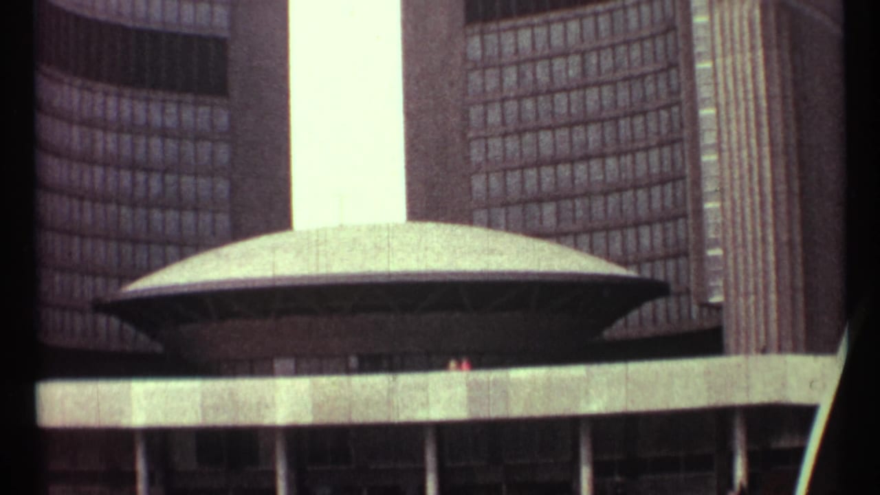 Oval chamber roof centered between tall curved building facades.