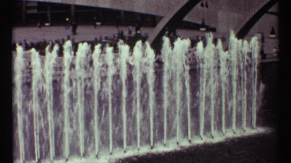 Vertical fountain sprays dominate this 1967 Toronto plaza view, with a modern facade and small pedestrian figures behind.