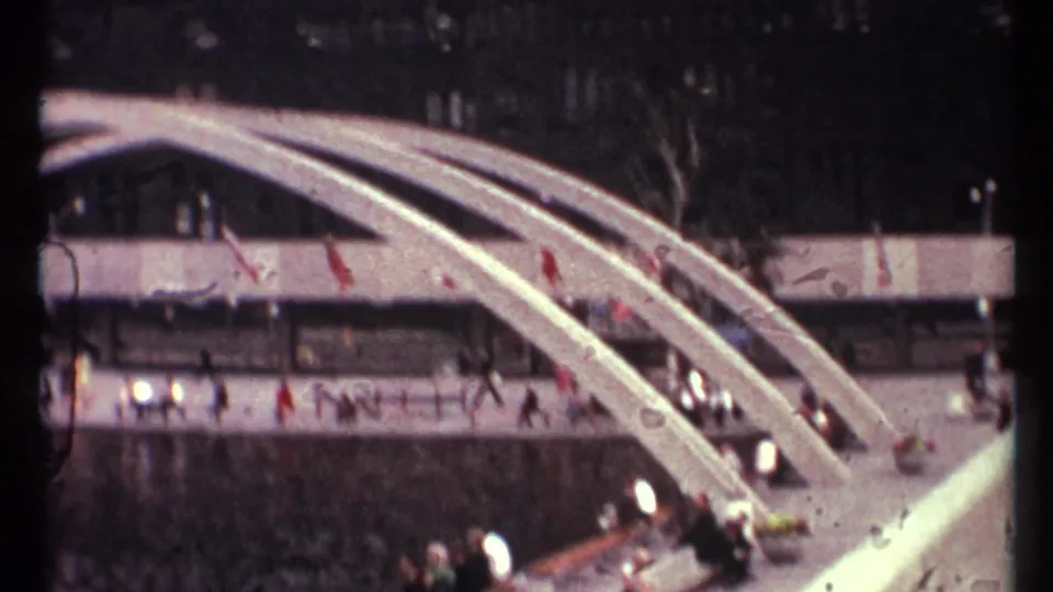 Toronto 1967 plaza scene showing white arched spans, people on walkways, red flags, and a dark urban backdrop.