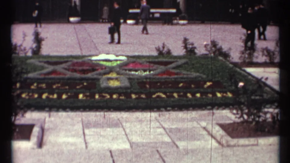 1967 Toronto civic floral bed with geometric planting, plaza paving, benches, shrubs, and pedestrians in period clothing.