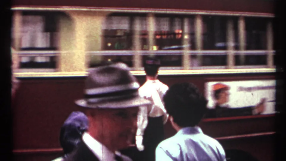 A red-and-cream Toronto transit vehicle passes as the white-gloved traffic director continues signaling in the street.