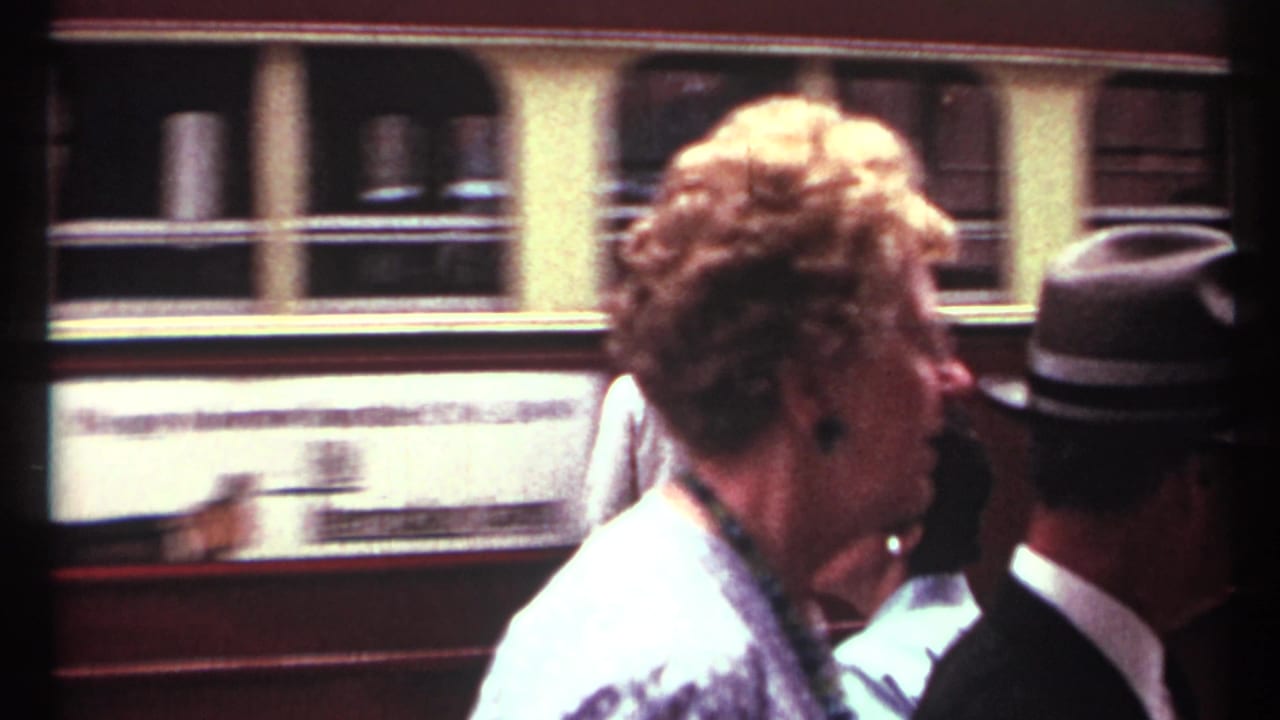 1967 Toronto street scene with pedestrians in period clothing passing in front of a moving streetcar or trolley.