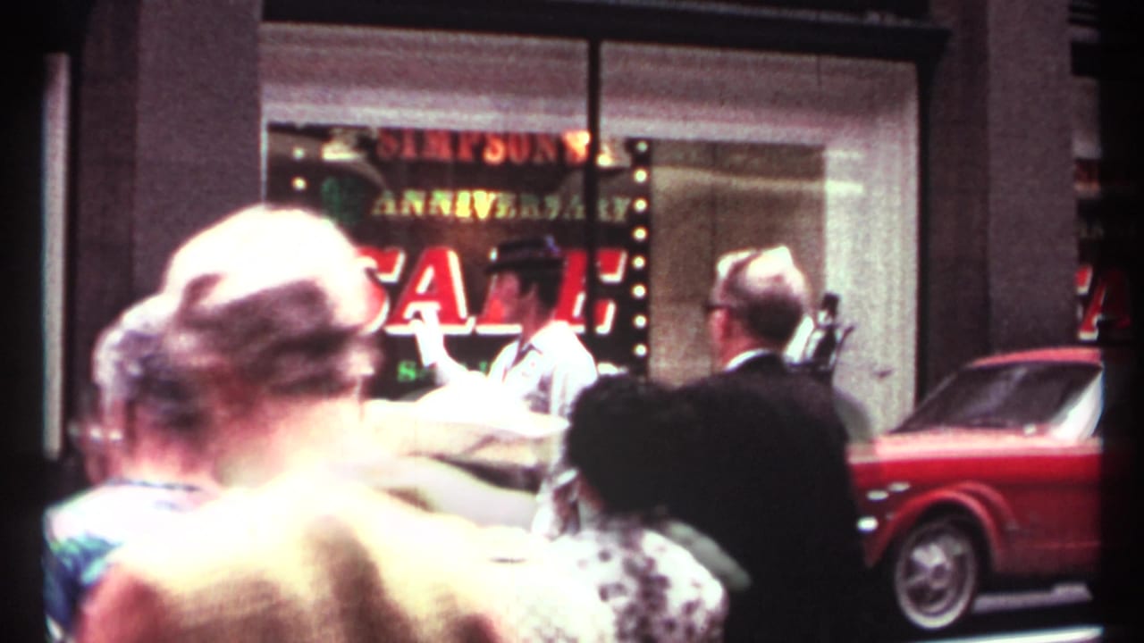 Crowd in front of a Simpson's sale window with a red Mustang at the curb.