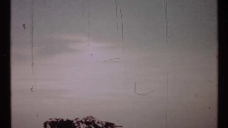 1967 Toronto 8mm frame showing open sky, film scratches, soft exposure bands, and a small strip of treetop at the bottom.