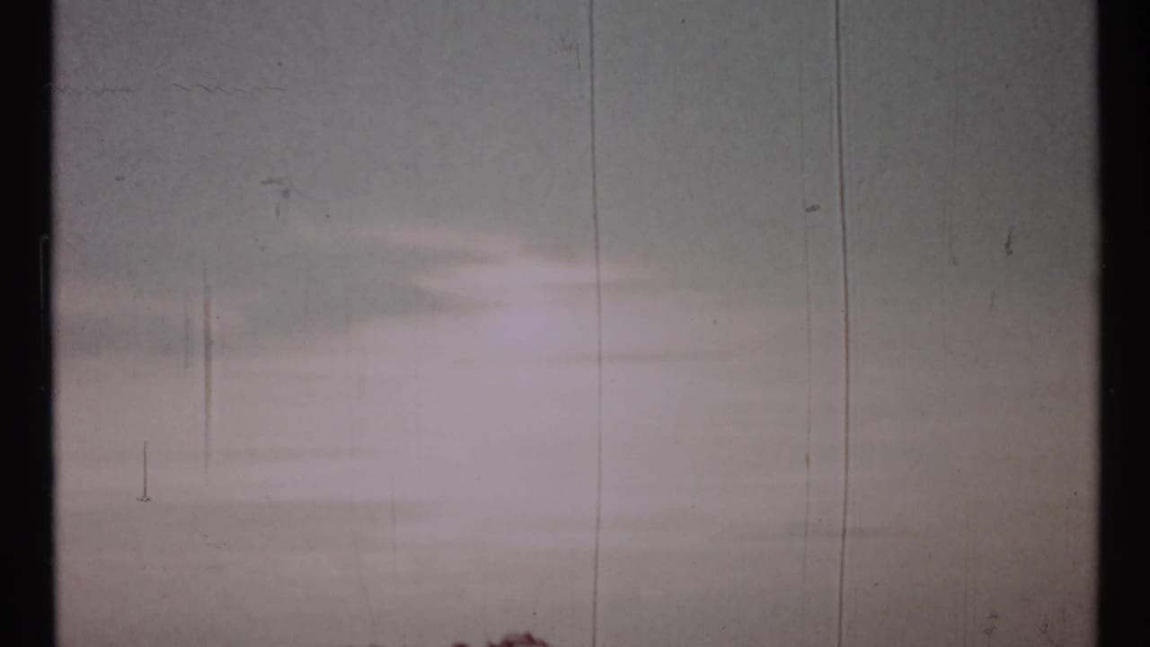 Mostly blank pale film frame with vertical scratches and faint exposure bands.