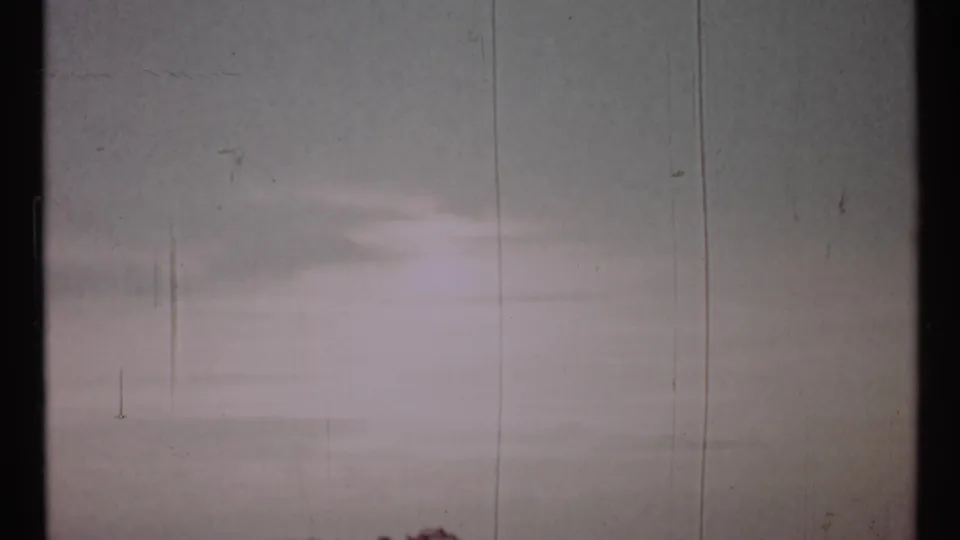 Opening 8mm frame appears nearly blank, with pale exposure, vertical film scratches, and no discernible street detail.