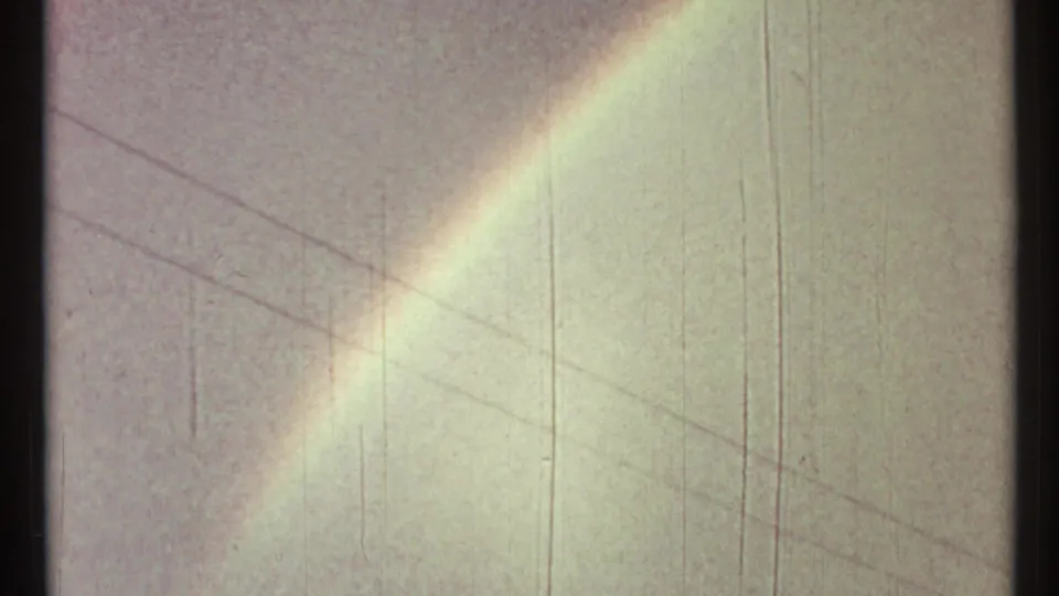 A faint rainbow cuts diagonally across the gray Toronto sky in this 1967 8mm frame, with utility lines visible.
