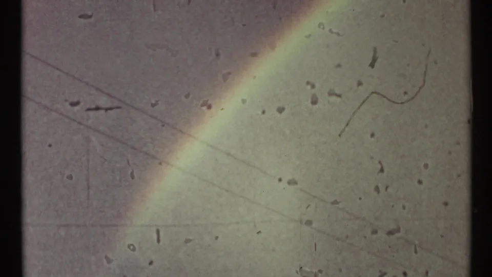 1967 Toronto frame with a soft diagonal rainbow, gray sky, faint overhead lines, and visible 8mm dust marks.