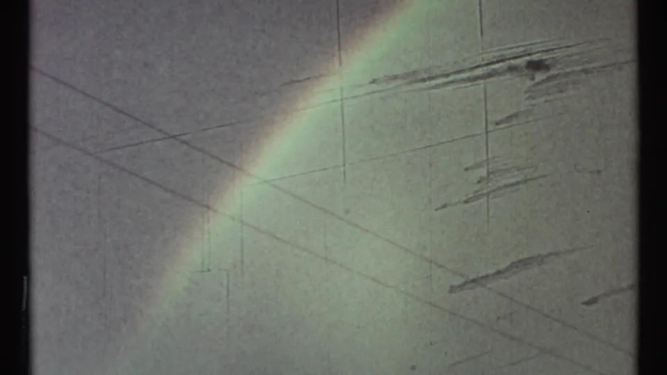 Faint rainbow over a cloudy sky in 1967 8mm footage, with soft fading, grain, and vertical film wear visible.