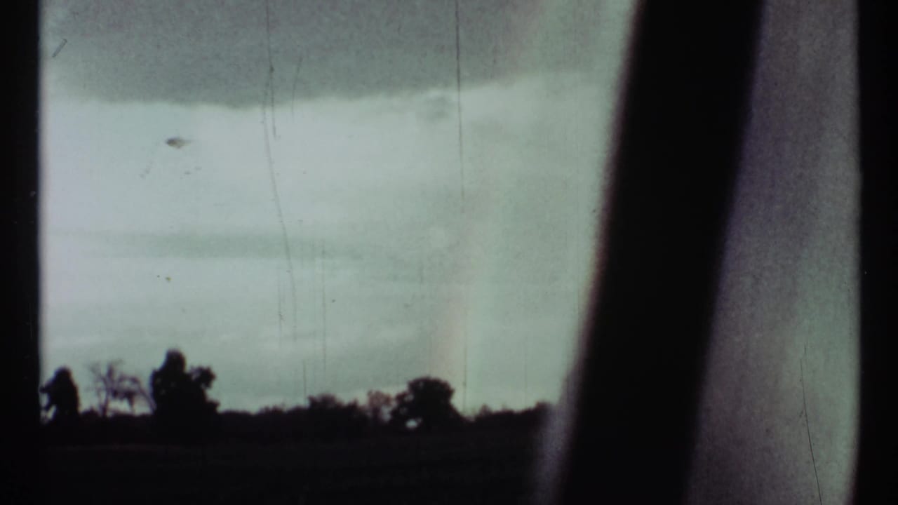 1967 Toronto 8mm frame showing a pale storm sky and dark treeline silhouette through vertical window framing.