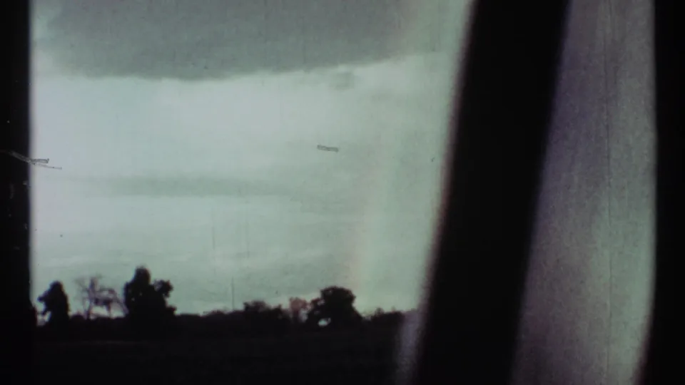 1967 Toronto 8mm view of pale cloud cover over a dark treeline, partially obscured by window framing.
