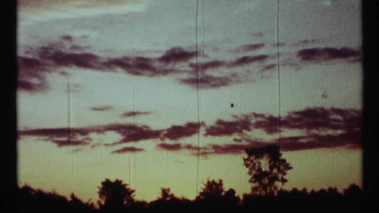 Cloud-streaked dusk sky with silhouetted trees in archival 8mm footage, supported by 1967 Toronto clip metadata.