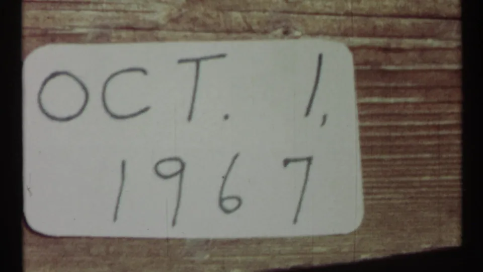 Handwritten date card marked Oct. 1, 1967, filmed close up on a wooden background with dark film edge visible.