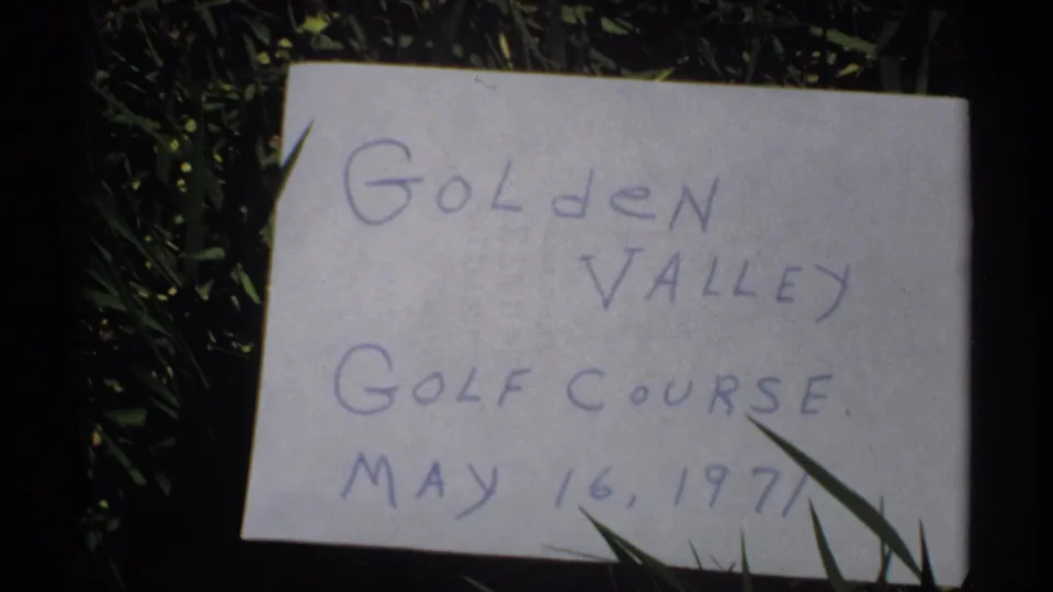 Close view of a handwritten Golden Valley Golf Course card dated May 16, 1971, placed among blades of grass.
