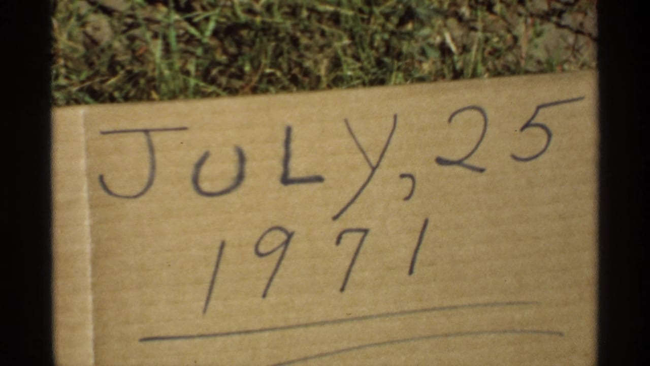 Handwritten cardboard sign reading July 25, 1971 on grass.