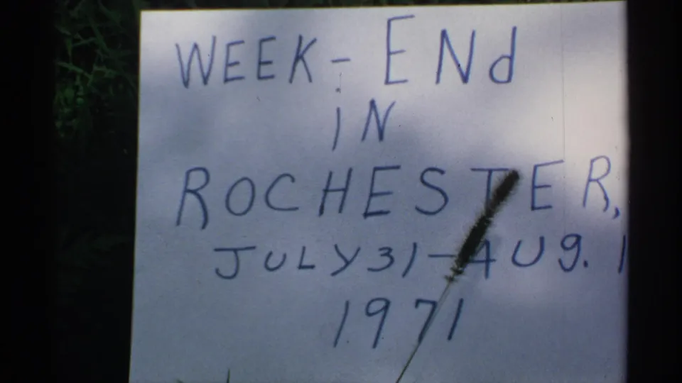 Close-up of the Rochester weekend title card, with blue handwriting and a plant stem obscuring part of the date.