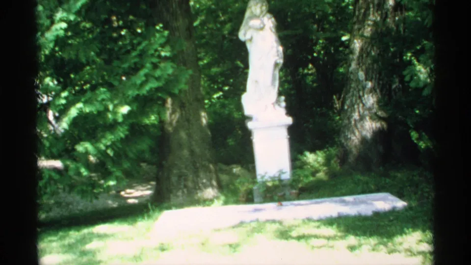 A second 1970 Minnesota view of the robed statue, framed by trees and overexposed grass.