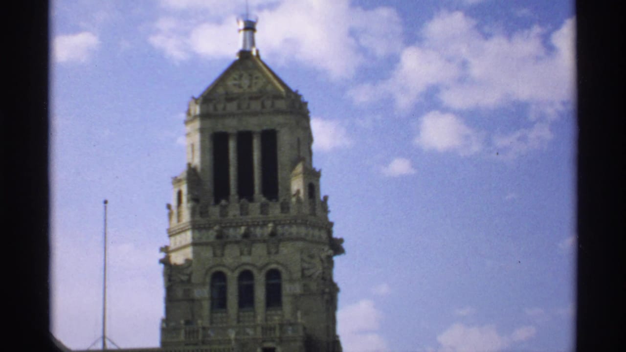 Ornate pale stone tower framed against blue sky and clouds.