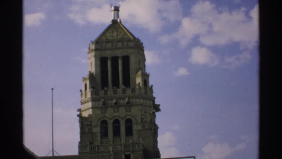 1970 Minnesota 8mm frame showing an upward view of the ornate tower, with softened focus and visible film borders.