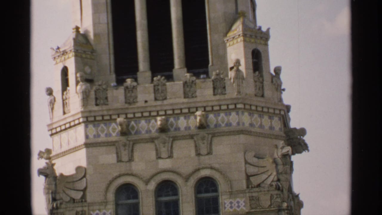 Ornate building top with arched windows, carved figures, and patterned tile bands.