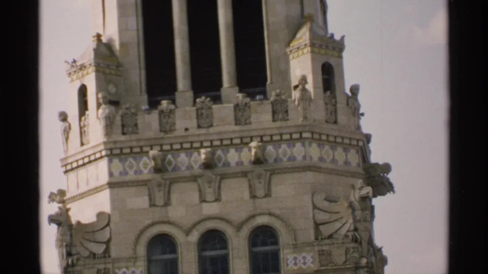 1970 Minnesota 8mm frame showing an ornate masonry building top with arched windows, carved figures, and decorative tilework.