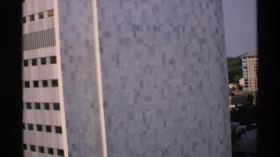 1970 Minnesota 8mm view of the same tiled skyscraper exterior, with gray wall panels, narrow windows, and a sliver of background skyline.