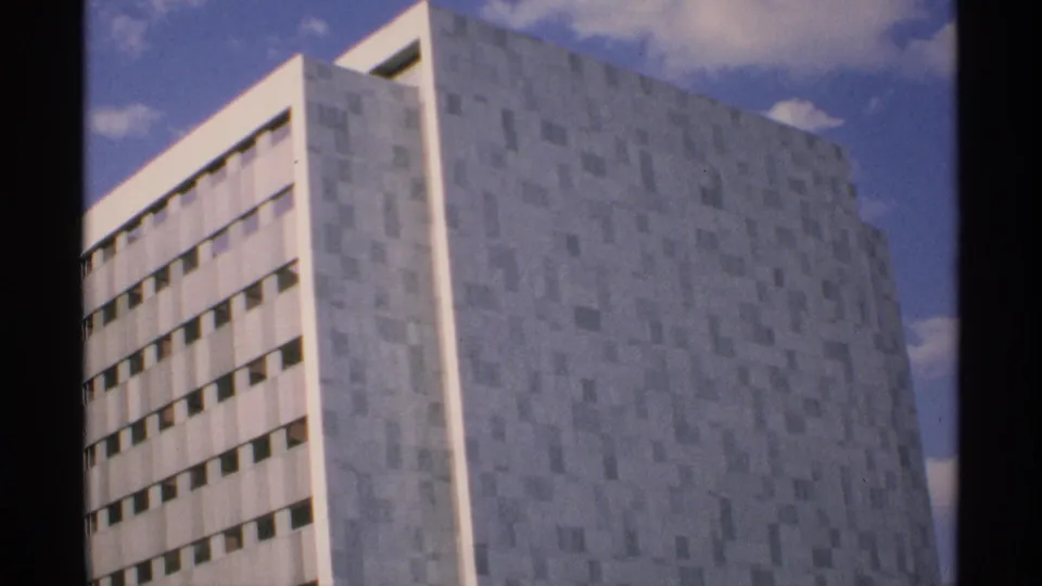 1970 Minnesota 8mm view of the same pale high-rise from an angle, showing window bands and a geometric facade.