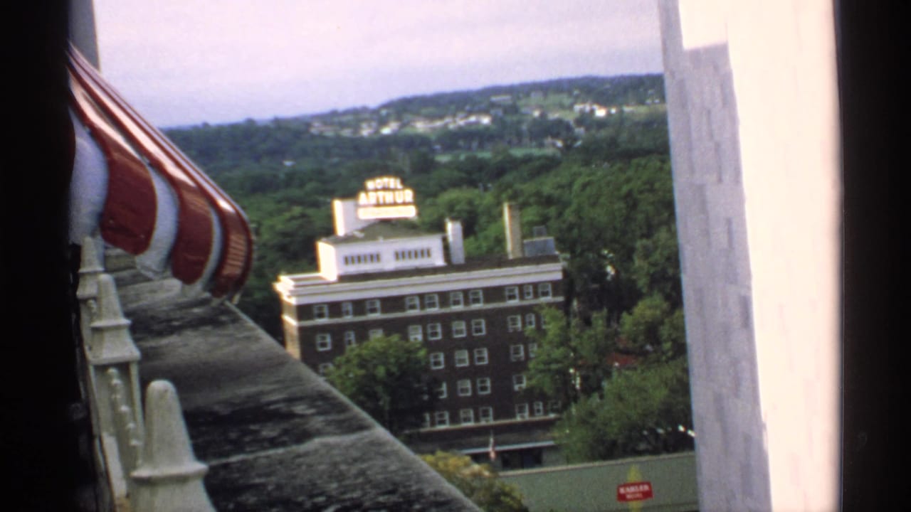 High view toward the Hotel Arthur sign and brick building beyond a striped awning and balcony ledge.