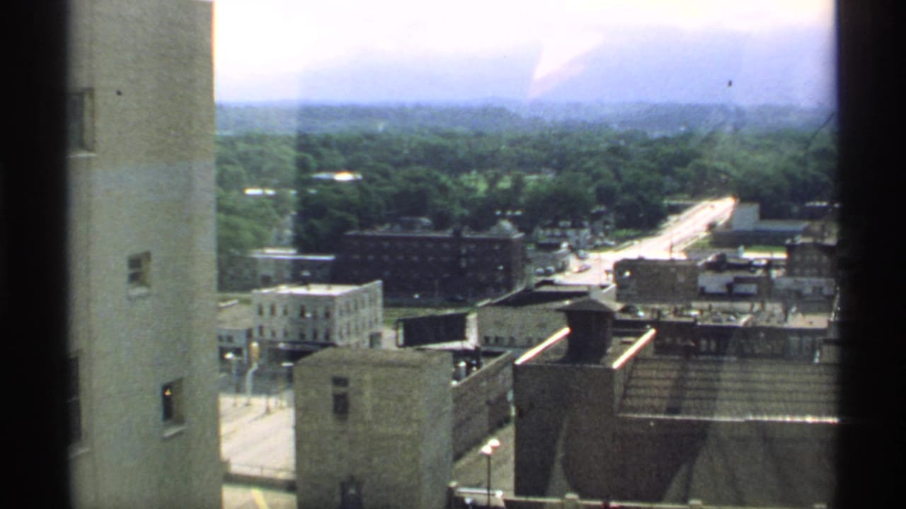 High-angle view over city rooftops and a distant road from an elevated vantage point.