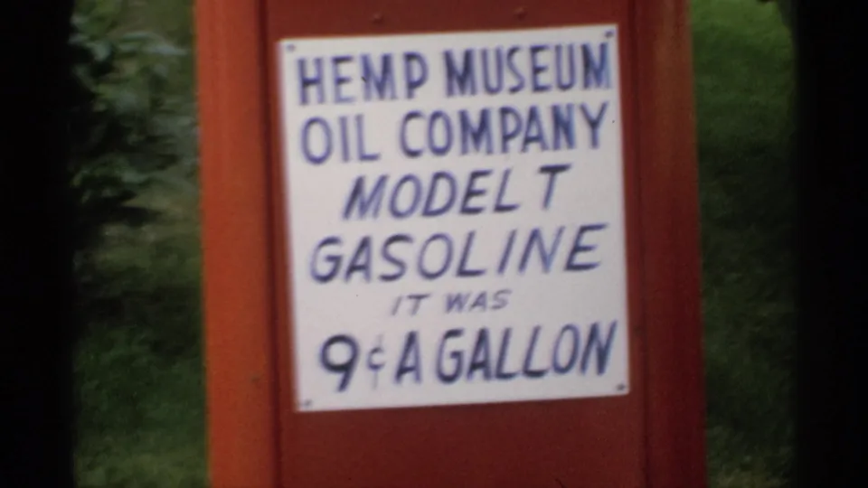 Close 1970 Minnesota home-movie view of the red museum pump sign advertising Model T Gasoline at 9 cents a gallon.