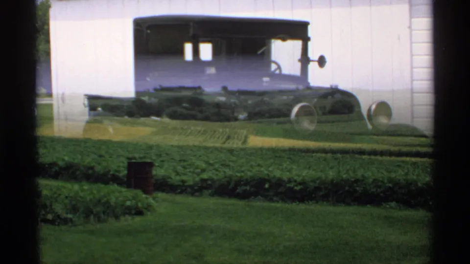 1970 Minnesota 8mm view across green farm fields, with a partial reflected or overlapping pickup shape near the top of the frame.
