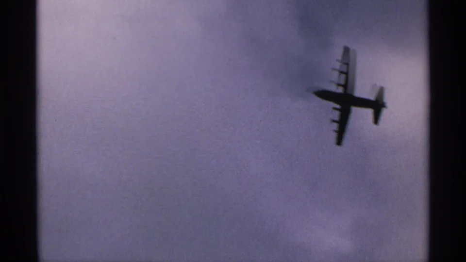 The airplane silhouette continues across a soft, cloudy sky in the short home-movie clip.