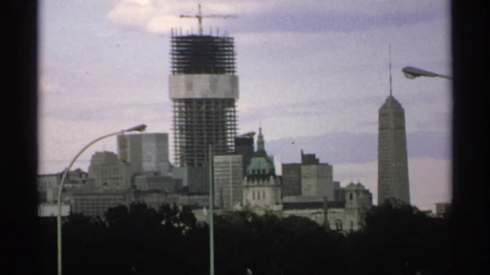 Minnesota downtown skyline in soft 8mm color, with an unfinished tower and crane rising over the city.