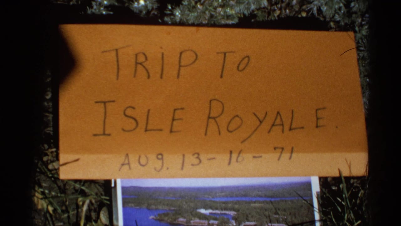 Handwritten cardboard sign reading Trip to Isle Royale with August 1971 dates above a small park photo.