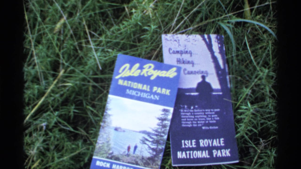 Two Isle Royale National Park brochures lying on green grass.