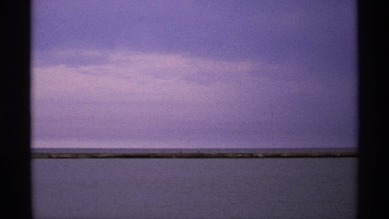 Purple dusk sky and calm lake horizon framed by dark film edges.