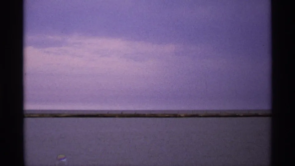 Isle Royale home-movie frame with a flat lake horizon, muted dusk sky, and visible 8mm frame borders.