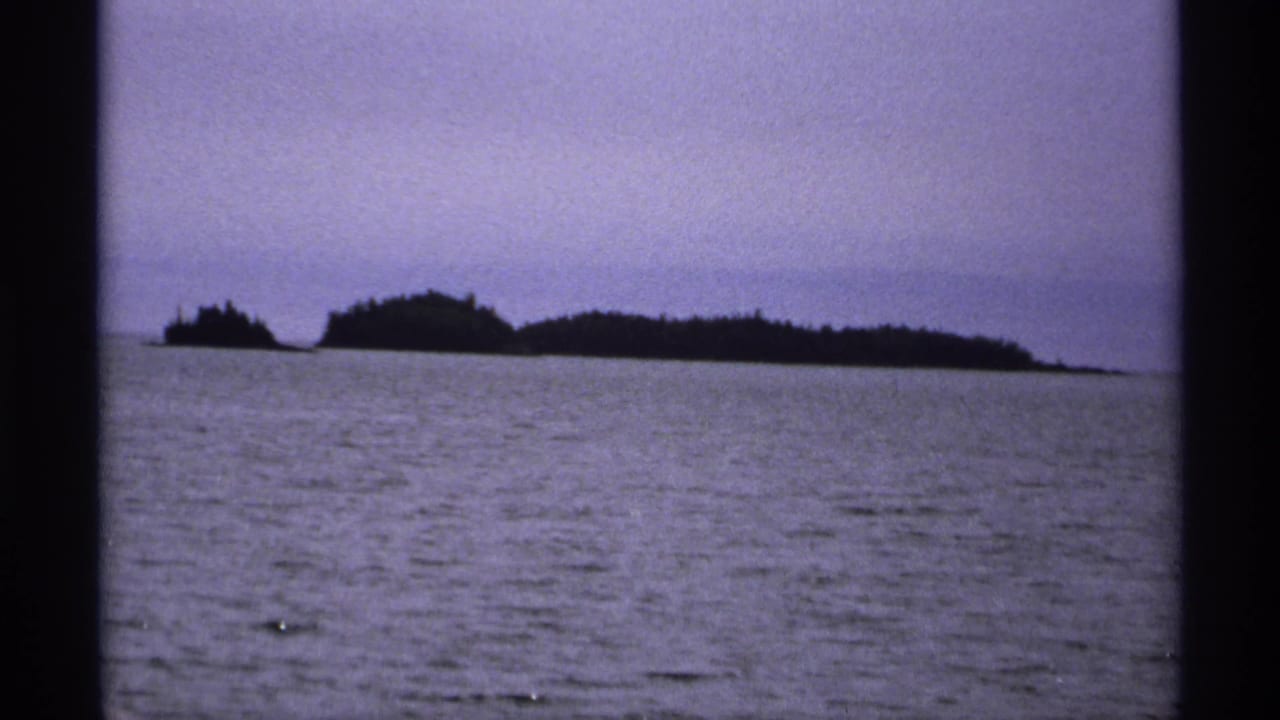 Distant dark island silhouettes across open water under a hazy sky.